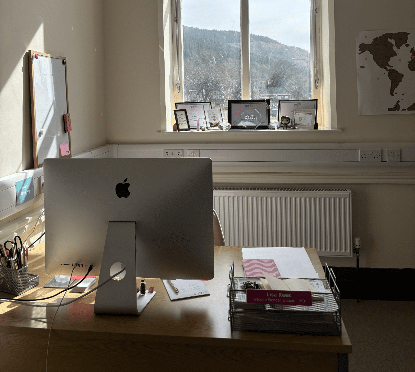 An experienced website designer's office, a desk with an Apple computer and a window with a view.