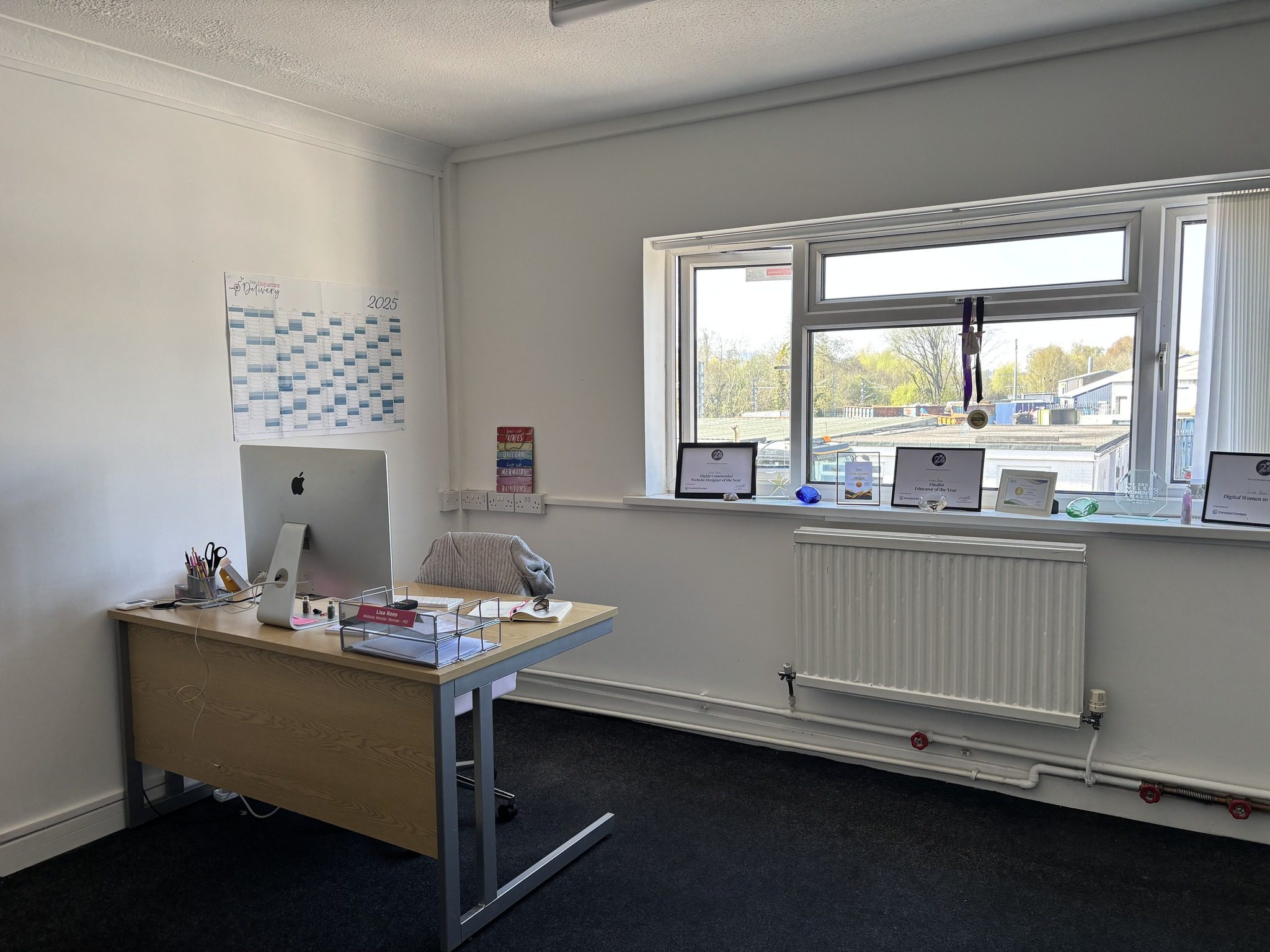 An experienced website designer's office, a desk with an Apple computer and a window with a view.