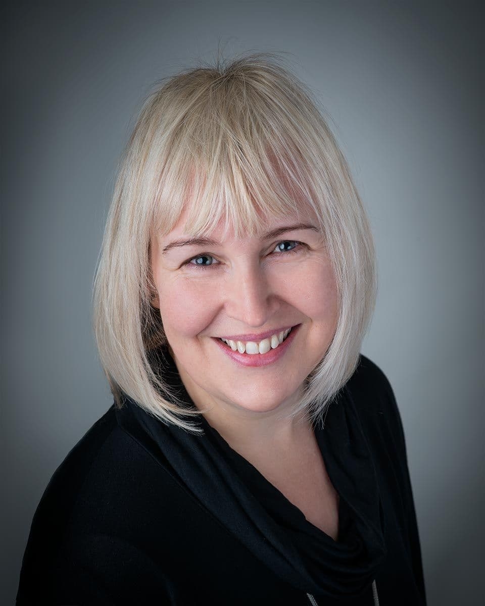 Heather the Content Creator A lady with blonde hair in a bob, smiling, wearing a black top
